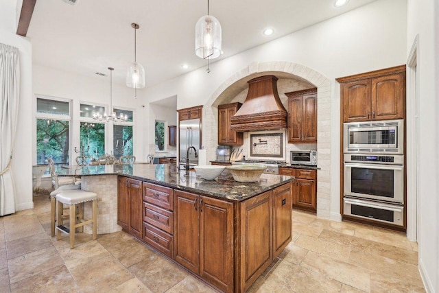 kitchen featuring dark stone counters, a large island, a toaster, premium range hood, and appliances with stainless steel finishes