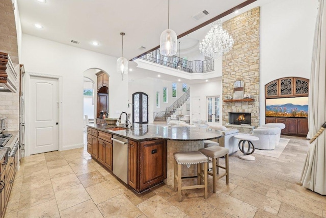 kitchen with arched walkways, stone tile flooring, a high ceiling, and a fireplace