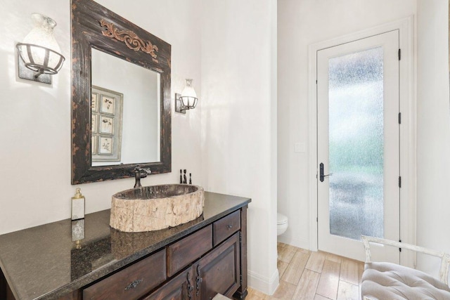 bathroom featuring wood finished floors, toilet, and vanity