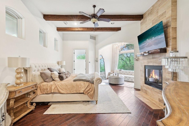 bedroom with visible vents, beamed ceiling, a tile fireplace, and dark wood-type flooring