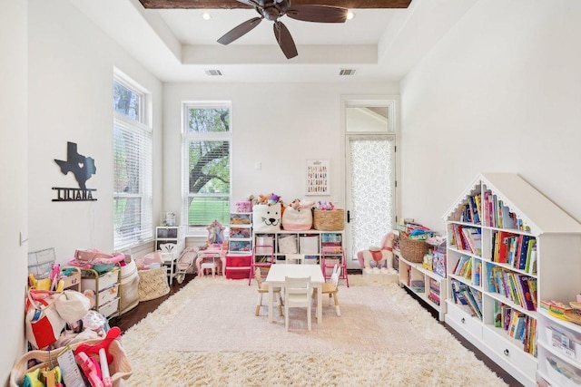 playroom featuring visible vents, a ceiling fan, and a tray ceiling