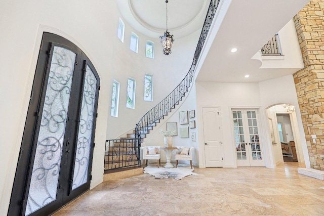 entryway featuring arched walkways, recessed lighting, french doors, a high ceiling, and stairs