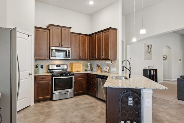 319 Silver Glen Dr, Kyle, TX 78640 - kitchen with stainless steel appliances, a peninsula, arched walkways, decorative backsplash, and a towering ceiling