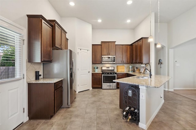 319 Silver Glen Dr, Kyle, TX 78640 - kitchen with stainless steel appliances, a peninsula, backsplash, light stone counters, and recessed lighting