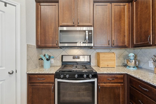 319 Silver Glen Dr, Kyle, TX 78640 - kitchen featuring appliances with stainless steel finishes, tasteful backsplash, and light stone counters