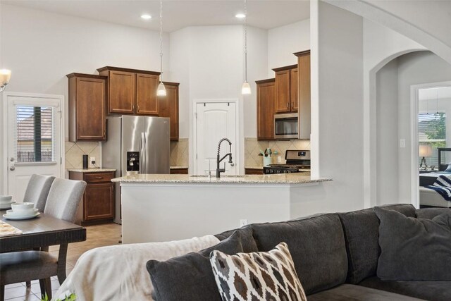 319 Silver Glen Dr, Kyle, TX 78640 - kitchen with open floor plan, appliances with stainless steel finishes, arched walkways, light stone counters, and a towering ceiling