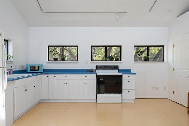 1005 Lisa Dr, Austin, TX 78733 - kitchen with electric stove, white cabinetry, light floors, and rail lighting