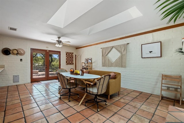 1005 Lisa Dr, Austin, TX 78733 - dining space featuring a skylight, french doors, brick wall, light tile patterned flooring, and a ceiling fan