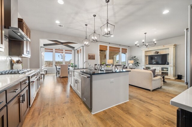 16319 Golden Top Dr, Austin, TX 78738 - kitchen with a chandelier, stainless steel appliances, wall chimney exhaust hood, recessed lighting, and light wood finished floors