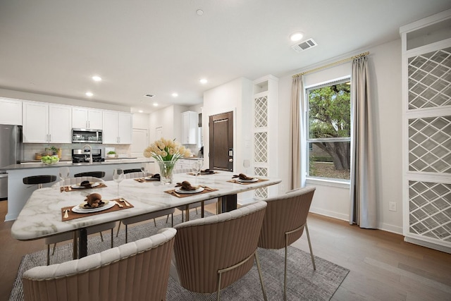2500 Forest Creek Dr Unit 2501, Round Rock, TX 78665 - kitchen with a breakfast bar area, light wood-style flooring, white cabinets, visible vents, and stainless steel appliances
