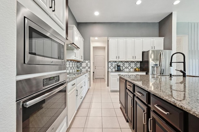 650 Ledge Stone Dr, Austin, TX 78737 - kitchen with appliances with stainless steel finishes, white cabinetry, light tile patterned floors, light stone countertops, and recessed lighting