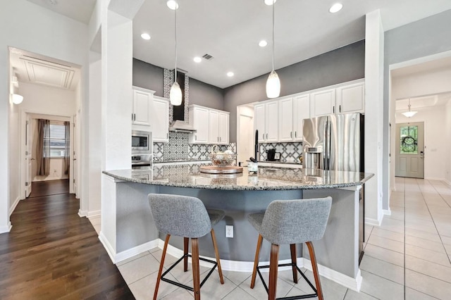 650 Ledge Stone Dr, Austin, TX 78737 - kitchen with appliances with stainless steel finishes, backsplash, white cabinetry, a large island with sink, and a breakfast bar