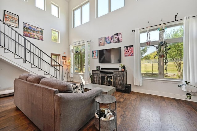 living area featuring baseboards, a high ceiling, dark wood finished floors, and stairs