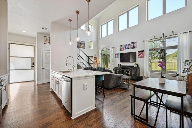kitchen with a sink, dark wood-style floors, white cabinets, pendant lighting, and dishwasher