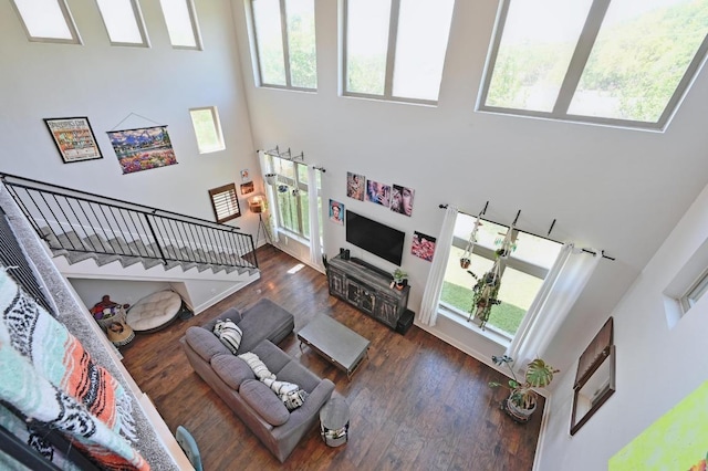 living area with a high ceiling, dark wood-style floors, and stairway