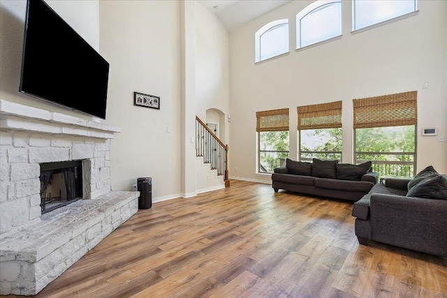 12907 Gordons Hvn, San Antonio, TX 78253 - living area with a towering ceiling, wood finished floors, a stone fireplace, stairs, and plenty of natural light