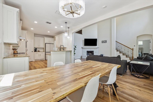 12907 Gordons Hvn, San Antonio, TX 78253 - dining space with a fireplace, light wood-style flooring, a chandelier, stairs, and recessed lighting
