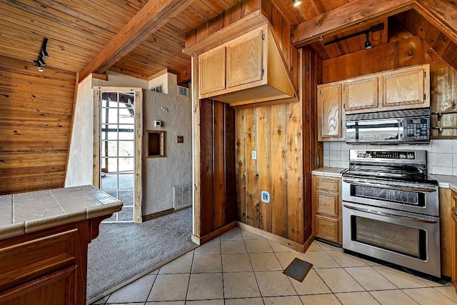 kitchen with visible vents, wooden ceiling, tile counters, black microwave, and range with two ovens