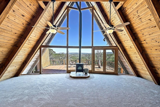unfurnished living room with carpet flooring, wooden ceiling, a wood stove, and a ceiling fan