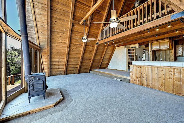 interior space with a wood stove, carpet, lofted ceiling with beams, and wood ceiling