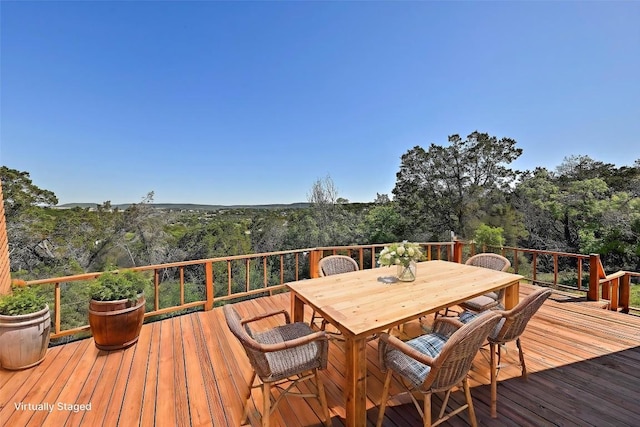 deck featuring a wooded view and outdoor dining area