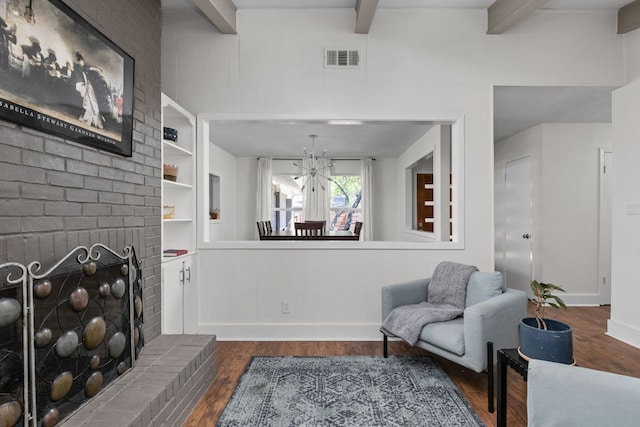 8604 Primrose Ln, Austin, TX 78757 - living area featuring beamed ceiling, dark wood-style floors, a chandelier, a brick fireplace, and built in shelves