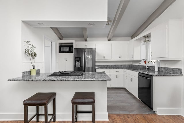 8604 Primrose Ln, Austin, TX 78757 - kitchen featuring black appliances, a peninsula, white cabinets, a kitchen breakfast bar, and dark wood finished floors