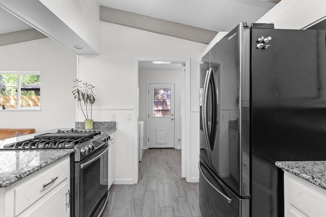 8604 Primrose Ln, Austin, TX 78757 - kitchen with freestanding refrigerator, stainless steel range with gas cooktop, vaulted ceiling, white cabinets, and light stone countertops