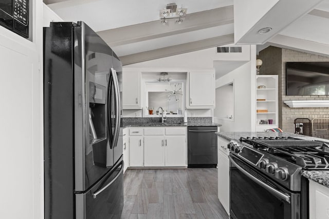 8604 Primrose Ln, Austin, TX 78757 - kitchen with appliances with stainless steel finishes, white cabinetry, dark stone countertops, and wood finished floors