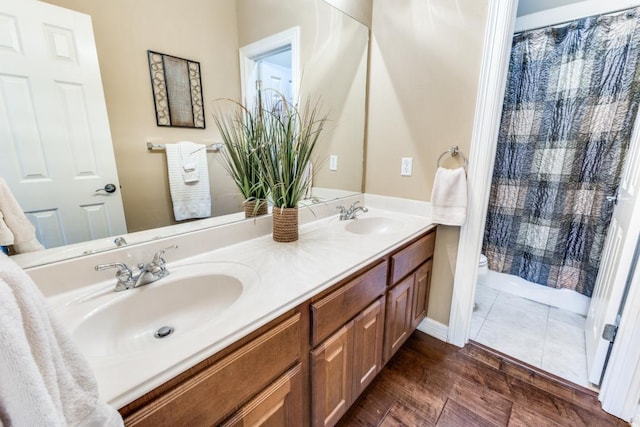 402 Palos Verdes Dr, Lakeway, TX 78734 - bathroom with toilet, double vanity, wood finished floors, a shower with shower curtain, and baseboards