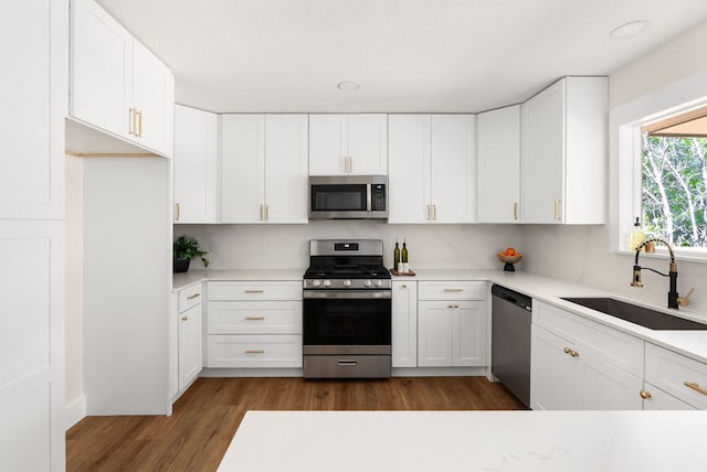 9005 Quail Creek Dr, Austin, TX 78758 - kitchen featuring stainless steel appliances, light countertops, wood finished floors, and white cabinets