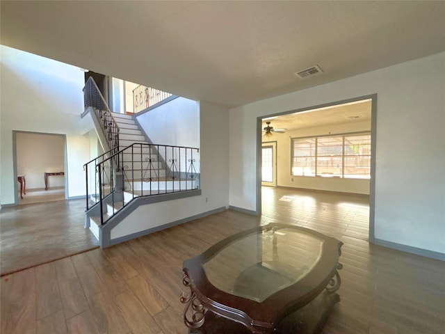 living room with visible vents, baseboards, a ceiling fan, wood finished floors, and stairs