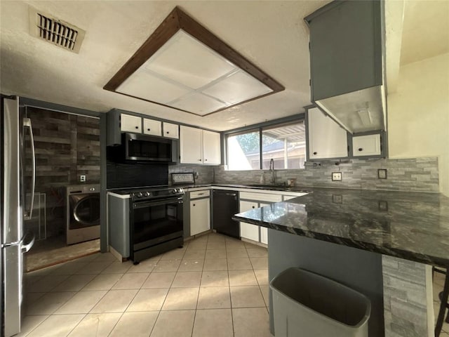 kitchen with a peninsula, visible vents, black appliances, a sink, and washer / dryer