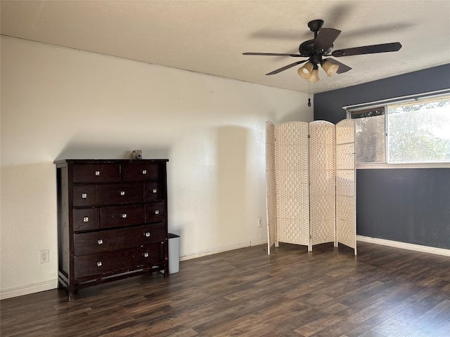 unfurnished bedroom with dark wood-style flooring, baseboards, and a ceiling fan