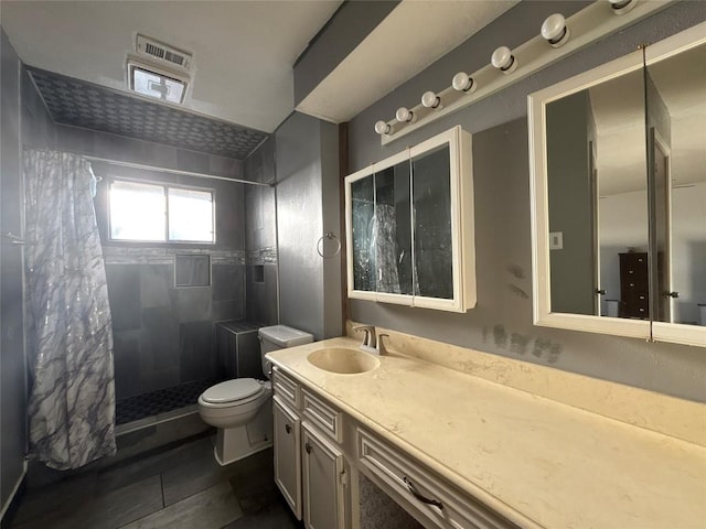 full bathroom with vanity, a tile shower, and toilet