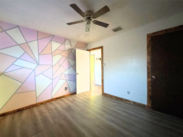 unfurnished bedroom with visible vents, baseboards, ceiling fan, and wood finished floors