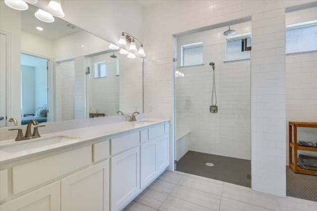 full bath featuring double vanity, visible vents, tile patterned flooring, a tile shower, and a sink