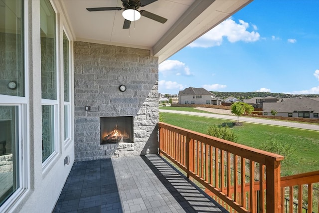 exterior space with an outdoor stone fireplace, ceiling fan, and a residential view