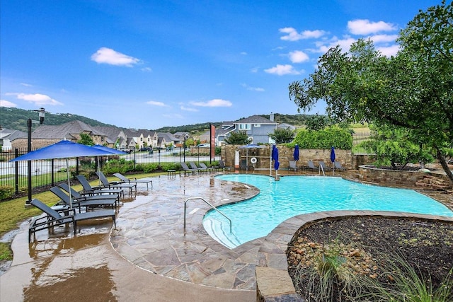 pool with fence, a patio, and a residential view