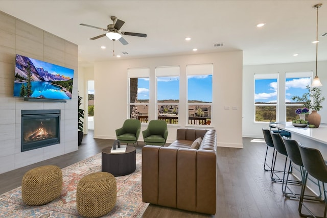 living area featuring visible vents, a ceiling fan, dark wood-style floors, and a tile fireplace