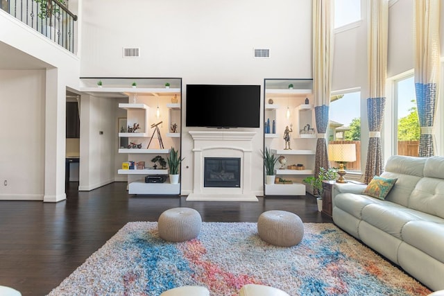2348 Centennial Loop, Round Rock, TX 78665 - living area with a towering ceiling, dark wood-type flooring, a glass covered fireplace, and baseboards