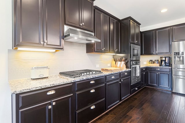 2348 Centennial Loop, Round Rock, TX 78665 - kitchen featuring under cabinet range hood, stainless steel appliances, dark wood finished floors, light stone counters, and decorative backsplash
