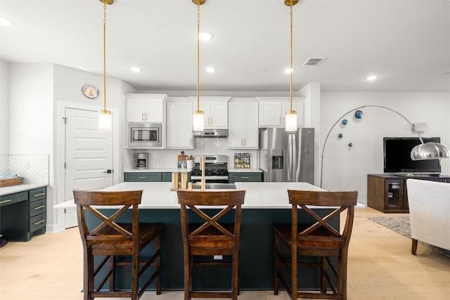 200 W 56th St Unit 4102, Austin, TX 78751 - kitchen featuring appliances with stainless steel finishes, extractor fan, decorative backsplash, light countertops, and white cabinets