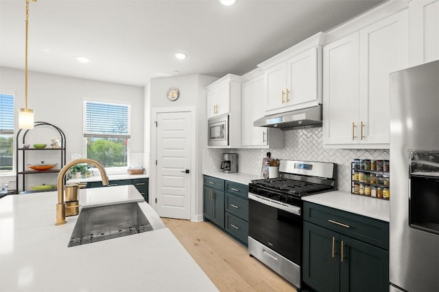 200 W 56th St Unit 4102, Austin, TX 78751 - kitchen featuring appliances with stainless steel finishes, extractor fan, white cabinetry, light countertops, and light wood-type flooring