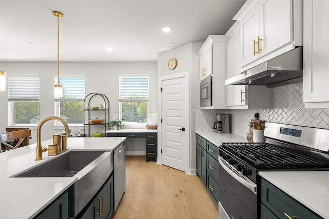 200 W 56th St Unit 4102, Austin, TX 78751 - kitchen featuring stainless steel appliances, white cabinetry, under cabinet range hood, light wood-style floors, and light countertops