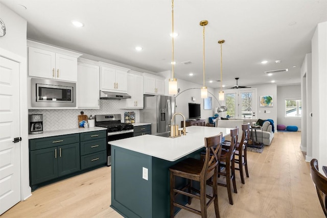 200 W 56th St Unit 4102, Austin, TX 78751 - kitchen featuring stainless steel appliances, under cabinet range hood, open floor plan, white cabinetry, and light wood-type flooring