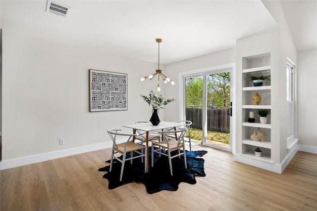 2702 Irish Bend Dr, Austin, TX 78745 - dining room with a chandelier, light wood finished floors, baseboards, and built in shelves