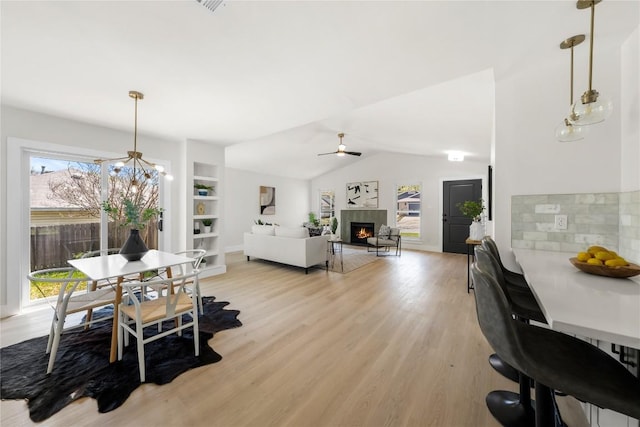 2702 Irish Bend Dr, Austin, TX 78745 - dining space with a wealth of natural light, vaulted ceiling, light wood-style floors, and a lit fireplace