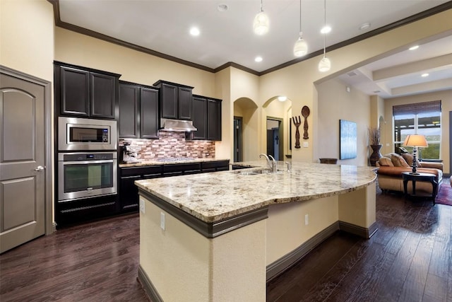 5612 Cherokee Draw Rd, Austin, TX 78738 - kitchen featuring appliances with stainless steel finishes, arched walkways, under cabinet range hood, decorative backsplash, and a large island
