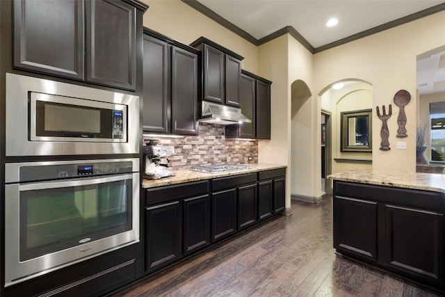 5612 Cherokee Draw Rd, Austin, TX 78738 - kitchen featuring stainless steel appliances, under cabinet range hood, ornamental molding, tasteful backsplash, and light stone countertops